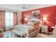 Cozy bedroom featuring floral bedding, bench seat, a ceiling fan and red accent wall at 4925 Poolside, St Cloud, FL 34769