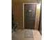 Neutral toned front door with small welcome decoration and potted plants on a tile front step at 6153 Metrowest Blvd # 103, Orlando, FL 32835