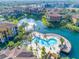 Aerial view of a beautiful community pool surrounded by palm trees and overlooking a scenic lake with fountain at 6153 Metrowest Blvd # 103, Orlando, FL 32835