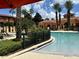 Resort-style pool area with lush landscaping, palm trees, and comfortable lounge chairs at 6153 Metrowest Blvd # 103, Orlando, FL 32835