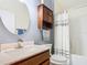 Bathroom with a wooden cabinet, round mirror, shower with white curtain, and chrome faucet at 649 Meadow Pointe Dr, Haines City, FL 33844