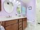 Stylish bathroom with a double sink vanity, decorative mirrors, and lilac colored walls at 649 Meadow Pointe Dr, Haines City, FL 33844