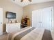 Comfortable tan bedroom featuring a ceiling fan, white dresser with TV, and built-in closet at 649 Meadow Pointe Dr, Haines City, FL 33844