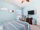 Light blue bedroom with a wooden dresser with TV, neutral carpet and a bright window at 649 Meadow Pointe Dr, Haines City, FL 33844