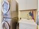 Bright laundry room featuring stacked washer and dryer units and a utility sink and cabinet at 649 Meadow Pointe Dr, Haines City, FL 33844