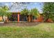 Exterior backyard featuring tropical landscaping, lush lawn, trees and the patio of the well-maintained home at 651 Highlands Hammock Dr, Poinciana, FL 34759