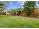 Backyard view featuring a well-maintained lawn, tropical landscaping, mature trees and the home's exterior at 651 Highlands Hammock Dr, Poinciana, FL 34759