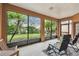 Enclosed lanai with comfortable seating offers serene views of the manicured backyard and lush tropical landscaping at 651 Highlands Hammock Dr, Poinciana, FL 34759