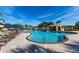 Beautiful resort-style pool featuring a rock waterfall, palm trees, and plenty of lounge chairs under blue umbrellas at 8974 California Palm Rd, Kissimmee, FL 34747