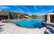Large community pool with a waterfall feature, surrounded by lounge chairs and blue umbrellas for relaxing by the water at 8974 California Palm Rd, Kissimmee, FL 34747