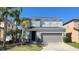 Charming two-story home featuring a two-car garage and lush tropical landscaping at 1113 Pine Ridge Dr, Davenport, FL 33896