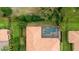 Aerial view of backyard pool with enclosure and barrel tile roof home surrounded by greenery at 11856 Vinci Dr, Windermere, FL 34786