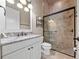 Elegant bathroom features granite countertops, framed mirror, and glass-enclosed shower with decorative tile at 11856 Vinci Dr, Windermere, FL 34786