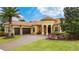 Elegant home featuring a tile roof, arched entryway, three-car garage, landscaped front yard and brick paved driveway at 11856 Vinci Dr, Windermere, FL 34786