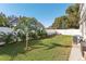 Large backyard featuring lush green lawn, tropical plants and white fence at 1205 Wisconsin Ave, St Cloud, FL 34769