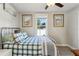 Cozy bedroom features a metal frame bed with a ceiling fan, artwork, and a bright window at 1205 Wisconsin Ave, St Cloud, FL 34769