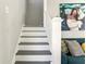 Carpeted staircase features white risers and railing, complemented by unique artwork and a cozy adjacent seating area at 1205 Wisconsin Ave, St Cloud, FL 34769
