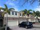Charming townhome showcasing lush palm trees, brick accents, paved driveway, and attached garage at 1509 Portofino Meadows Blvd, Orlando, FL 32824