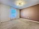 Spacious carpeted bedroom features neutral walls, a window, and a modern light fixture at 1510 Chelsea Dr, Davenport, FL 33897