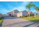 Charming single-story home with a brick driveway, arched entry, well-maintained landscaping, palm tree and an attached garage at 153 Cambridge Ave, Davenport, FL 33896