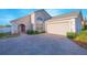 Charming single-story home with a brick driveway, arched entry, well-maintained landscaping, and attached two-car garage at 153 Cambridge Ave, Davenport, FL 33896