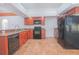 Spacious kitchen featuring dark appliances, wooden cabinets, granite countertops, tile flooring and access to more rooms at 153 Cambridge Ave, Davenport, FL 33896