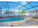 Fully screened pool with a safety fence, landscaping, and patio furniture at 153 Cambridge Ave, Davenport, FL 33896