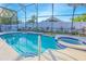 Inviting screened-in pool and spa area with lush landscaping for privacy at 153 Cambridge Ave, Davenport, FL 33896