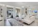 Bright and spacious living room featuring an open floorplan, modern lighting, white L-shaped sofa and access to the backyard pool at 1800 Tropical Palms Cir, Kissimmee, FL 34747
