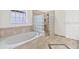 Bathroom featuring soaking tub, glass block shower, travertine tile, and tiled flooring at 2250 Windcrest Lake Cir, Orlando, FL 32824