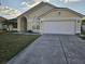 Charming one-story home featuring a manicured front yard and attached two-car garage at 231 Old Mill Cir, Kissimmee, FL 34746