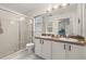 Bright bathroom with double sinks, large mirror, and glass enclosed shower at 248 Breezy Oaks Ct, Davenport, FL 33896