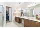 Bright bathroom with double vanity, large mirror, and glass-enclosed shower next to a walk-in closet at 309 Vestrella Dr, Poinciana, FL 34759