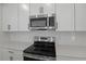 Contemporary stainless steel microwave and electric range stand above white quartz countertops and backsplash at 3725 Deer Ridge Dr, Mount Dora, FL 32757