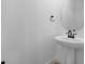 Modern powder room featuring a pedestal sink, round mirror, and sleek black fixtures at 3725 Deer Ridge Dr, Mount Dora, FL 32757