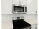 Close-up of modern kitchen featuring stainless steel appliances, sleek white cabinets and solid surface countertop at 3741 Deer Ridge Dr, Mount Dora, FL 32757