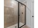 Modern bathroom with a glass-enclosed shower featuring beige tile surround and matte black hardware at 3757 Deer Ridge Dr, Mount Dora, FL 32757
