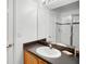 Well-lit bathroom featuring a single sink, black countertop, wood cabinets and a glass-door shower at 509 Cadiz Loop, Davenport, FL 33837