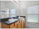 Bathroom with double sinks, wood cabinets, black countertops and a glass-door shower at 509 Cadiz Loop, Davenport, FL 33837