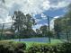 Well-maintained tennis court enclosed by a fence, surrounded by lush greenery and mature trees at 5160 Conroy Rd # 1414, Orlando, FL 32811