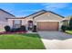 Charming single-Gathering home featuring a well-manicured lawn and a two-car garage with a classic brown door at 5457 Animosh Ct, Polk City, FL 33868