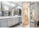 Bright bathroom featuring mirrored walls, a double sink vanity with marble countertop, and a glass-enclosed shower at 6 Escondido Cir # 58, Altamonte Springs, FL 32701