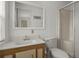 A well-lit bathroom featuring a single sink vanity, a toilet, and a walk-in shower at 6475 Peppertree Ne Path, Winter Haven, FL 33881