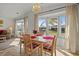 Sunlit dining area with a table set for four, views of the outdoors, and an elegant light fixture at 6475 Peppertree Ne Path, Winter Haven, FL 33881