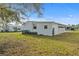 Rear view of home showcasing the siding, windows, and well-maintained lawn at 6475 Peppertree Ne Path, Winter Haven, FL 33881