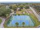 Aerial view of pristine blue and green tennis courts surrounded by lush greenery and palm trees at 734 Olympic Cir # 30, Ocoee, FL 34761