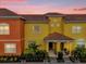 Colorful townhome at dusk featuring a red tile roof and inviting front entrance at 8971 Majesty Palm Rd, Kissimmee, FL 34747