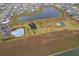 Aerial view of a community featuring a pool, playground, tennis court, and walking path around a pond at 9012 Tuscan Cypress St, Kissimmee, FL 34747