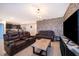 Open-concept living room featuring a stylish accent wall, leather seating, and seamless transition into the kitchen area at 9012 Tuscan Cypress St, Kissimmee, FL 34747