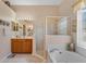 Bright bathroom featuring a soaking tub, walk-in shower, and double vanity with wood cabinets at 141 Prestwick Dr, Davenport, FL 33897